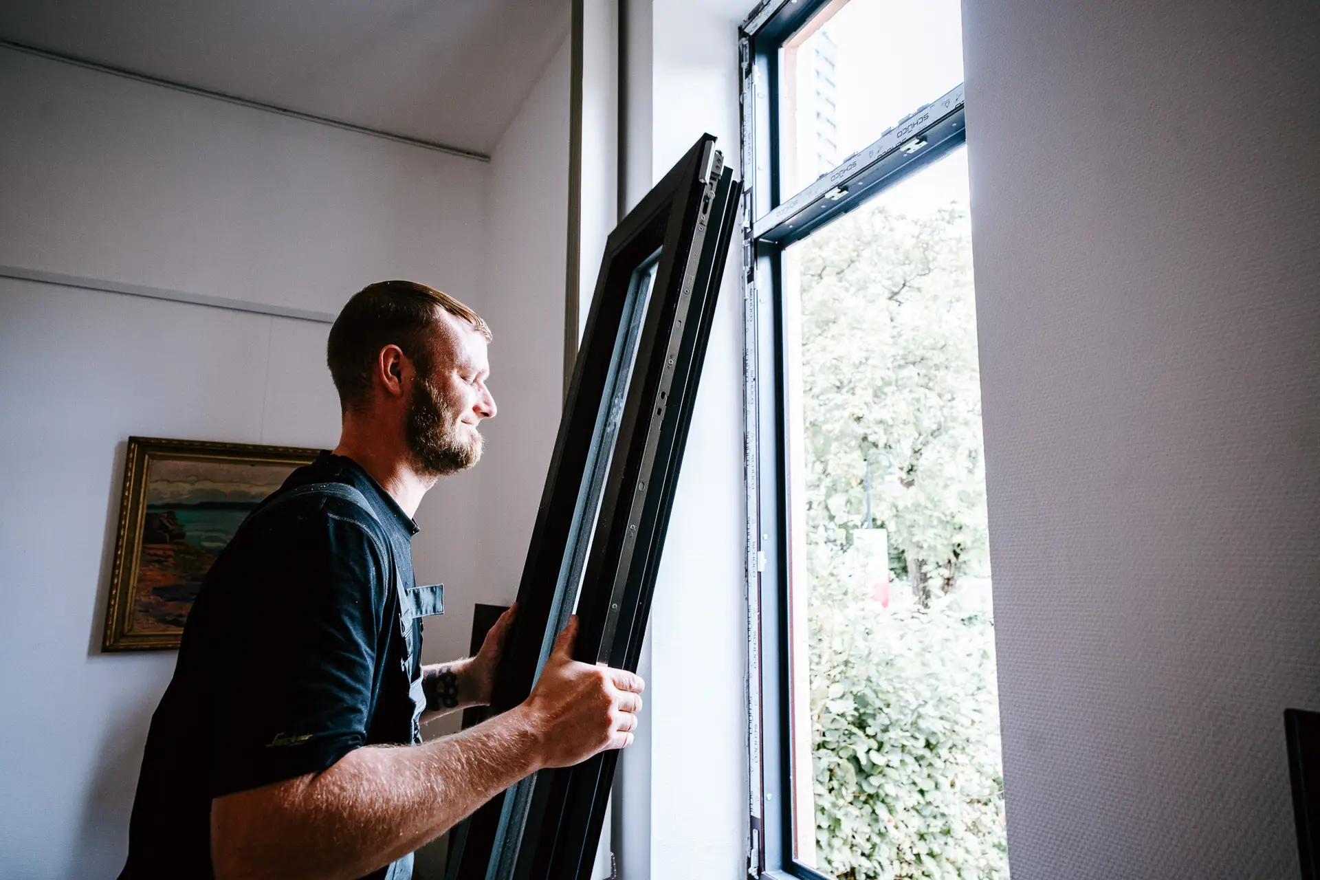Tischler setzt einen neuen Fensterflügel in einen Holzrahmen ein